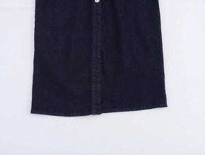 Détail d'une robe midi en jean bleu foncé montrant des boutons argentés et des coutures