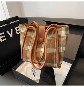 Close-up of wool plaid tote bag with brown leather handles and textured fabric