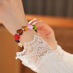 Colorful heart-shaped glass bead bracelet with white pearls worn on a wrist