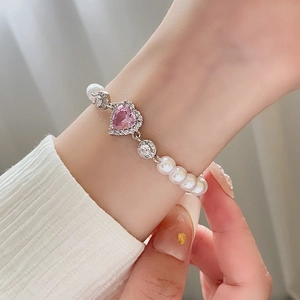 Elegant pearl bracelet with a pink heart zircon and sparkling rhinestones on hand