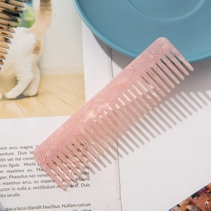 Pink marble texture acetate wide-tooth comb for hair styling on a vintage book page