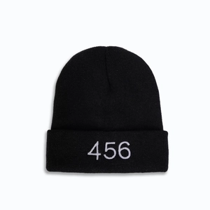 Dettaglio del ricamo bianco 456 su un berretto in maglia nera con risvolto classico