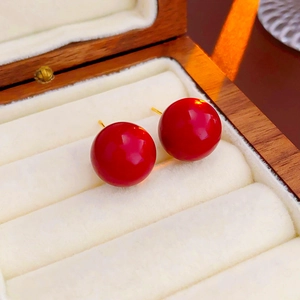 Gros plan d'élégantes boucles d'oreilles perles rouges sur du velours blanc bijoux