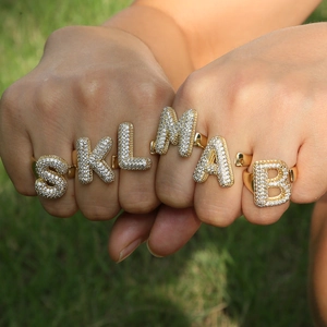 Macro detail of 3D gold-plated bubble letter rings with micro-pave white zircon stones