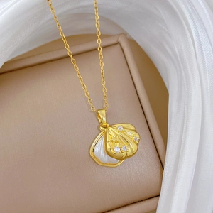 Vista macro di una collana con ciondolo a conchiglia dorata con inserto bianco e diamanti