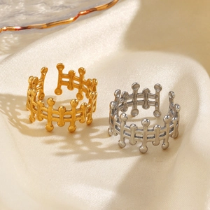 Gold and silver hollow geometric stainless steel open rings on beige silk fabric