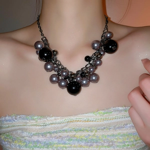 Detail of irregular pearl tassel necklace featuring gun-black metal chains and dark beads