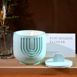Detail showing a light blue textured gypsum candle jar with flame on a wood base