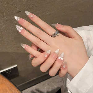 Pink French almond press-on nails with white butterfly bows and delicate pearl flowers