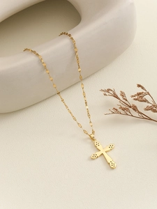 Detailed view of a gold cross necklace with micro-pave colored zircon on a white background