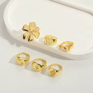 Detail of six gold-plated minimalist flower and butterfly rings on a white display tray