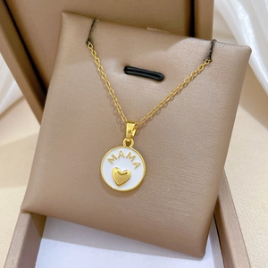 Close-up of golden MAMA heart pendant necklace with rhinestones on a brown jewelry cushion