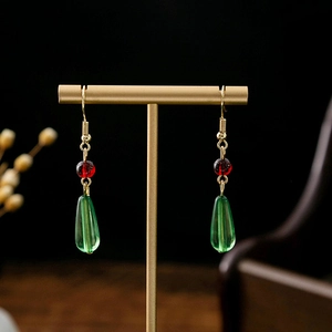 Detailed close-up of long tassel earrings with red beads and green drop pendants