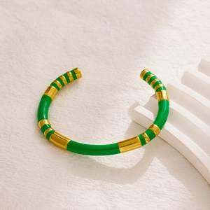 Detail of green and gold striped enamel on a polished stainless steel cuff bracelet