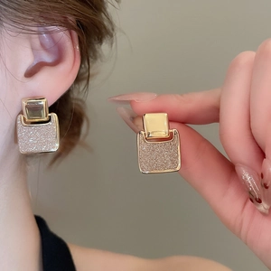 Detail view of 18k gold plated square earrings with pink shimmering glitter inlay texture