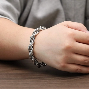 Close-up of a silver stainless steel braided chain bracelet worn on a female wrist