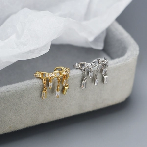 Vista macro di ear cuff con frange argento e oro, maglie a catena e zirconi lucidi
