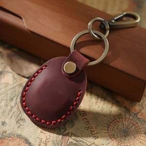Vintage brown leather AirTag holder with brass keyring on a retro map background