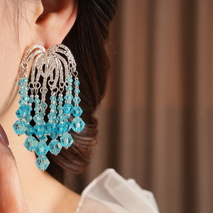 Detailed view of light blue crystal bead tassel earrings worn by a model in close-up shot