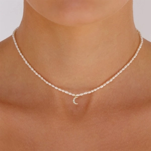 Close-up of a gold moon pendant with sparkling diamonds on a white pearl necklace