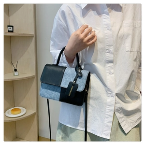 Detail of color-block square handbag with black leather and blue textured patchwork