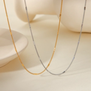 Minimalist gold and silver stainless steel chain necklaces displayed on cream stone props