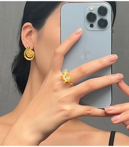 Close-up of elegant gold butterfly ring and spiral earrings set with colored gemstones