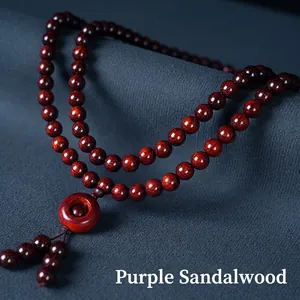 Polished red sandalwood 108 beads Buddhist necklace with tassel on textured background