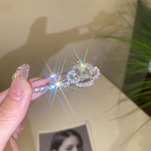 Detailed close-up of a silver crown brooch featuring sparkling crystals and tassel details