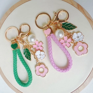 Detail of pink and green floral keychains with woven rope and golden rhinestone charms