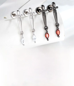 Macro detail of sword dangle earrings with zircon inlays and threaded flat back studs