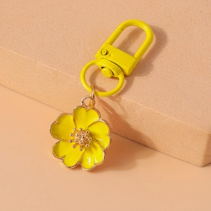 Macro detail of yellow enamel flower keychain with gold metal spring clasp and ring