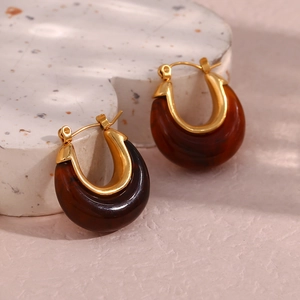 Detailed view of U-shaped earrings featuring amber resin and polished gold metal accents