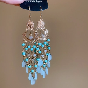 Close-up of bohemian tassel earrings with turquoise beads and gold filigree accents