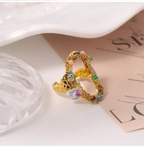 Detail of gold heart ring with pleated texture and colorful natural stone inlay on a tray