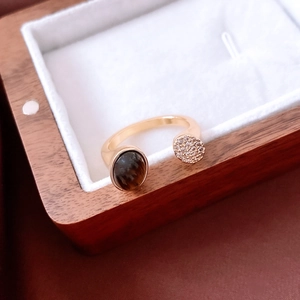 Detail of 18K gold-plated ring with tiger eye stone and zircons on a wooden jewelry box