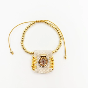 Close-up of religious fabric charm bracelet with gold steel beads and adjustable cord