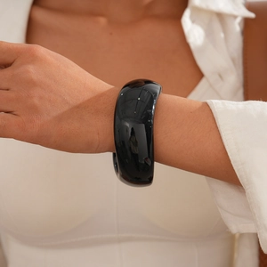 Polished wide black acrylic bangle bracelet showing glossy finish on woman's wrist