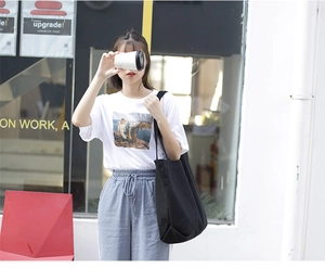 Minimalist black canvas tote bag shown as a casual shoulder bag for outdoor street style