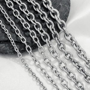Polished silver stainless steel O-link chains in various sizes on dark stone and satin