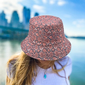Close-up of reddish-brown snake skin bucket hat with texture on outdoor female model