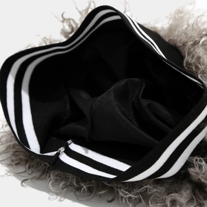 Detail of gray faux fur texture and black striped ribbed knit cuff on winter beanie