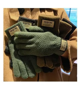 Various colors of thick knitted winter gloves featuring ribbed cuffs and warm labels