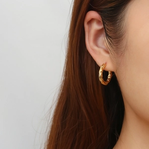 Detail of vintage gold C-shape earrings with a textured lava finish on model