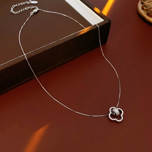 Detailed close-up of 18K gold plated clover flower pendant necklace on a jewelry box
