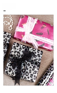 Close-up of leopard print and pink brushstroke gift wrap with elegant lace and ribbons