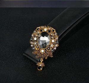 Macro view of vintage gold floral brooch with grey gemstone and crystal pendant detail