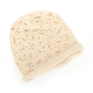 Detail of handmade crochet flower pattern on cream knit beanie with ribbed edge texture