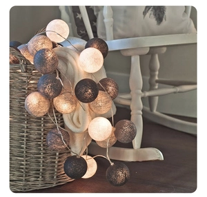 Detail of warm LED cotton ball string lights in grey and white on a cozy blanket