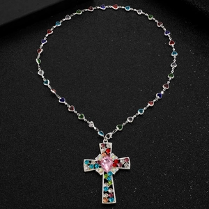 Macro detail of silver cross pendant necklace with colorful gems and pink heart crystal